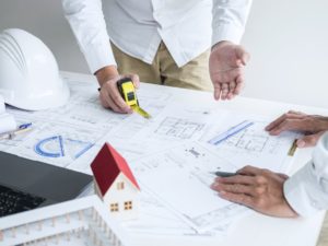 Construction engineering or architect discuss a blueprint while checking information on drawing and